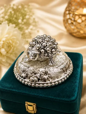 A shiny silver showpiece featuring a detailed turtle figurine mounted on a decorative floral base.