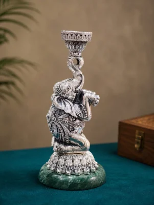This decorative silver elephant figurine features an oxidised finish with intricate carvings and sits on a circular green stone base.