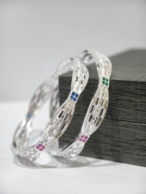 Silver bangles featuring a patterned openwork design studded with sparkling white stones and colourful accent stones.