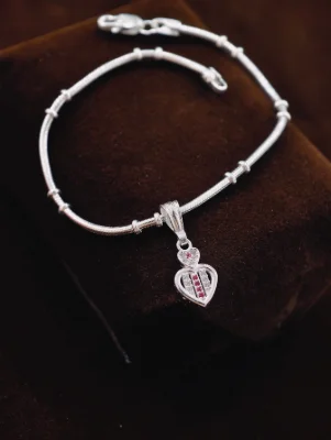 Silver chain bracelet featuring a heart pendant with red and white stones.