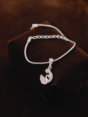 This silver chain bracelet features a delicate swan shaped pendant with embedded white stones and an adjustable link chain.