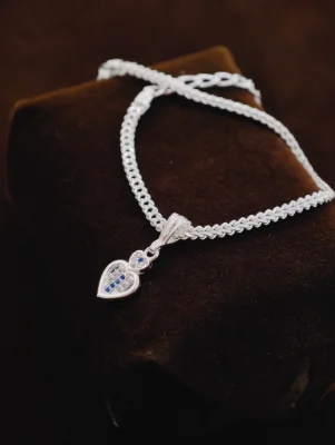Silver chain bracelet featuring a double heart pendant set with white and blue stones.
