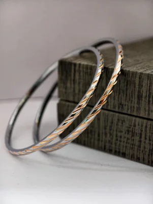 Pair of round silver bangles featuring a twisted patterned design with dual finish.