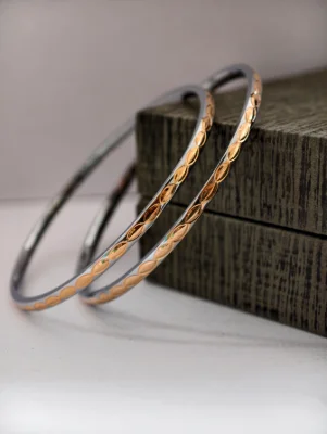 These round silver bangles feature a repeated leaf pattern with polished finish and golden highlights.