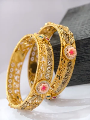 Gold polished silver bangles featuring intricate filigree patterns, leaf motifs, and pink floral designs with small multi-colored stones.