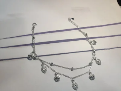Delicate double chain silver bracelet featuring small dangling evil eye and flower charms with sparkling white stones.