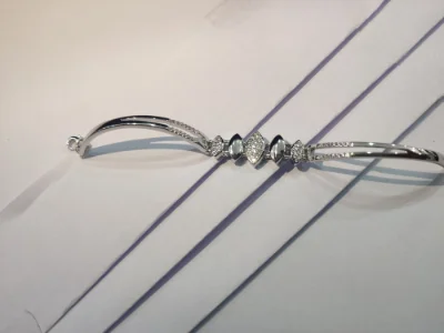A sleek silver bracelet featuring delicate marquise shaped patterns and embedded sparkling white stones in a modern double line design.