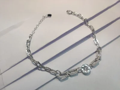 This lightweight silver bracelet features geometric link patterns and sparkling white stones with a shiny polished finish.