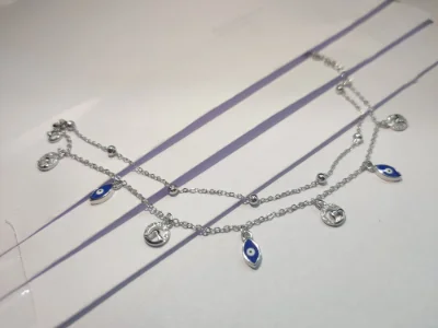 Silver double layer bracelet featuring dangling blue evil eye charms and round motifs.