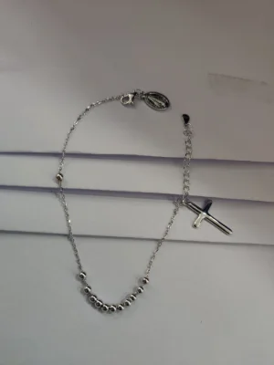 A light silver chain bracelet featuring small shiny beads and a cross pendant.